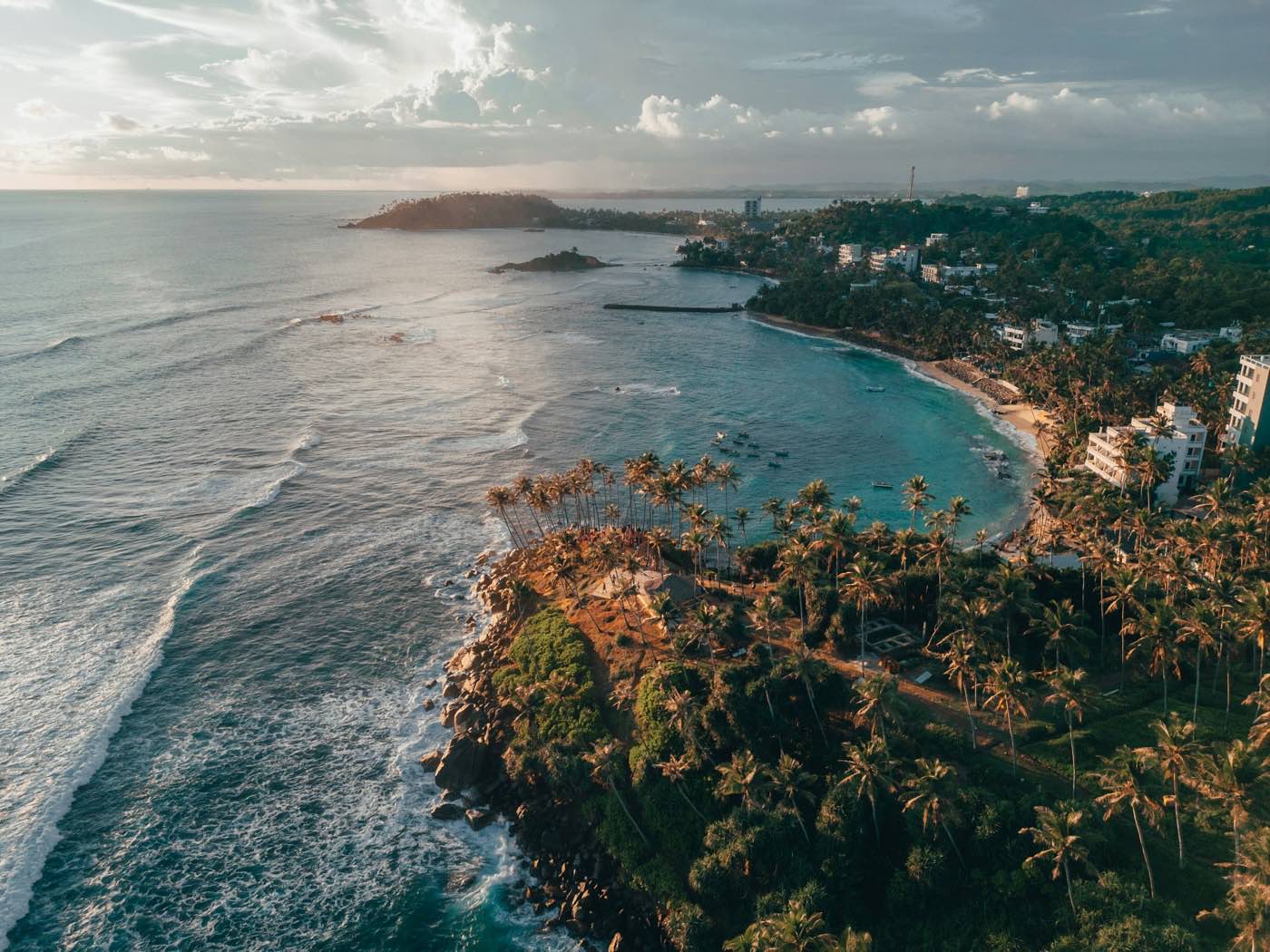 Aerial view at sunset of the palm-covered headland and turquoise bay at Mirissa on Sri Lanka’s south coast